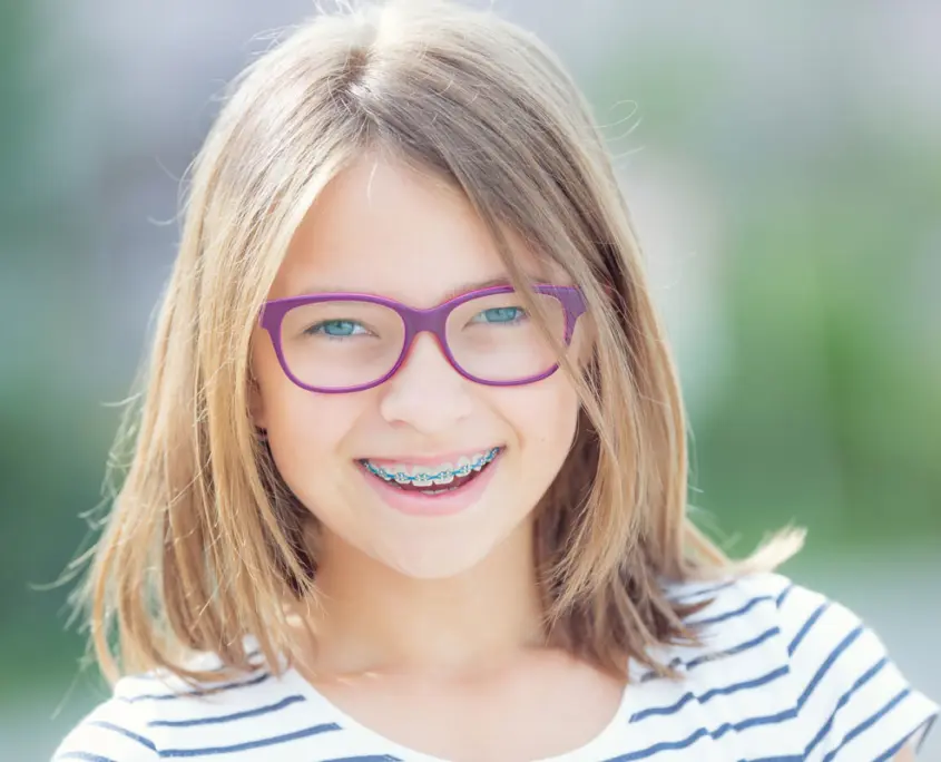Junges Mädchen lächelt nachdem ihr eine feste Zahnspange vom Kieferorthopäden eingesetzt wurde